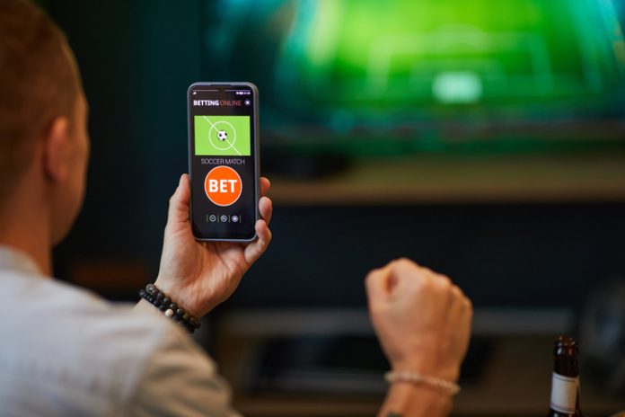 Betting Online on Soccer Match with Smartphone Person engaged in online soccer sports betting technoloy