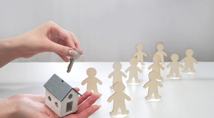 Camlo Looper Expands Supportive Housing Access Through THC Leadership Hand holding a model of a house and a key, offering it to figures of people. Supportive housing concept