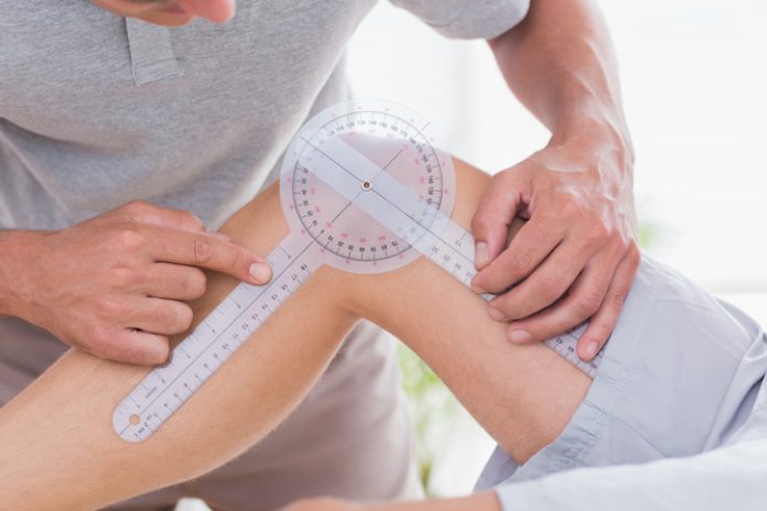 Doctor examining man leg Goniometer