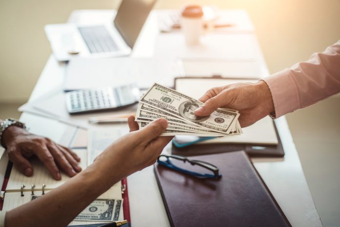 Hand of business man giving money for taking bribe while making contract. bribery and corruption concept. Hand of business man giving money for cash loans