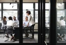 Why Strategy Isn’t Just for CEOs – and How to Implement It Millennial businesswoman stands addressing colleagues and thinking new strategy at a meeting, seen through glass wall