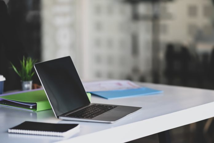 Side view of mock up laptop computer and document file on conference table. Enterprise-grade Hosting: Essentials for Large Companies