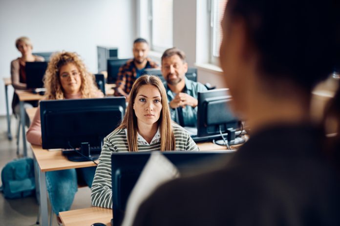 Mid adult woman attending computer class in the classroom. College student listening to the professor during lecture about AI