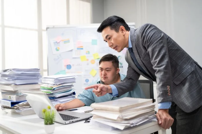 Asian young businessman with down syndrome working in office workplace. Employee man with autism or special needs brainstorm plan and discuss project with manager leader. Corporate of modern colleague Employee man with autism or AuDHD at Work brainstorm plan and discuss project with manager leader. Corporate of modern colleague