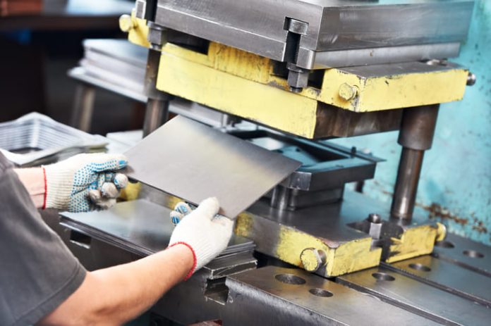 worker at manufacture workshop operating metal press machine in Mica Insulation