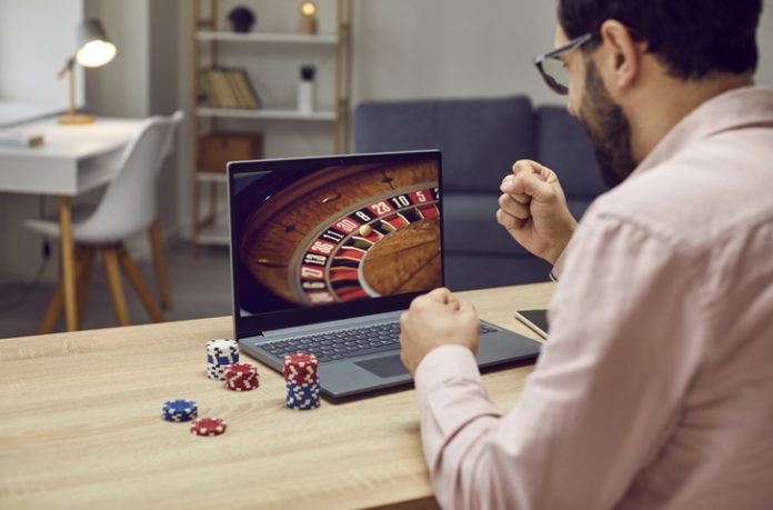 Gambler man playing online roulette game celebrating win Online Casino Promotions