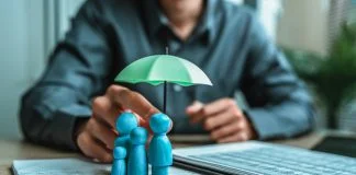 A wooden doll under an umbrella holding by agent represent life insurance and term insurance