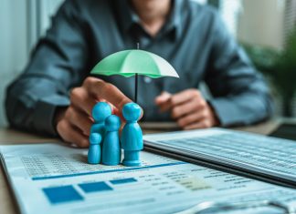 A wooden doll under an umbrella holding by agent represent life insurance and term insurance