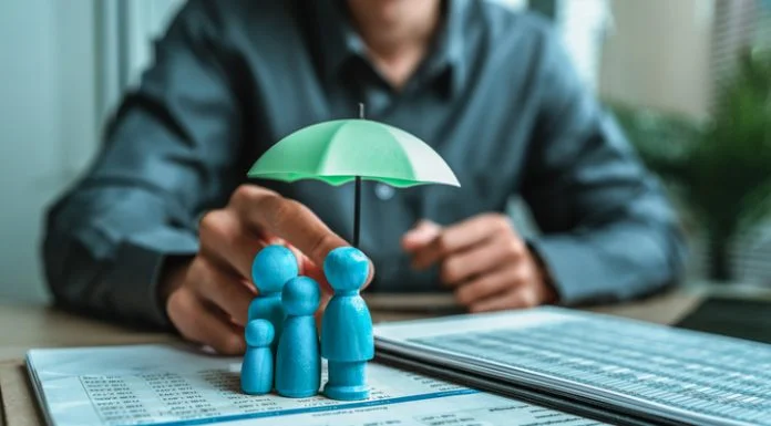 Life Insurance vs Term Insurance: When Should You Choose a 1 Crore Term Plan? A wooden doll under an umbrella holding by agent represent life insurance and term insurance