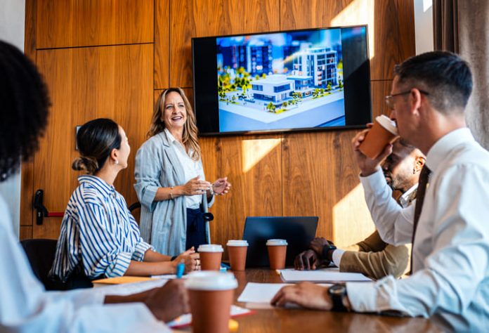 iStock-2245010911 (1) employees in the workplace watching blockbuster video as presentation during a meeting