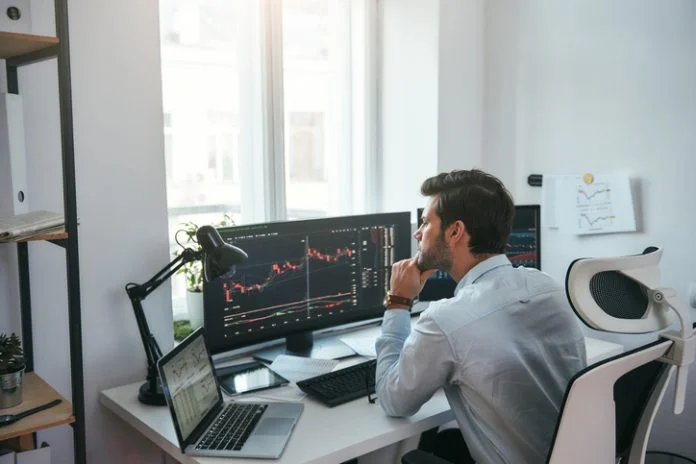 Trading on world markets. Young stock market broker analyzing data and graphs on multiple computer screens while sitting in modern office WeMasterTrade — A Prop Firm Platform Focused on Trader Development and Real Progress