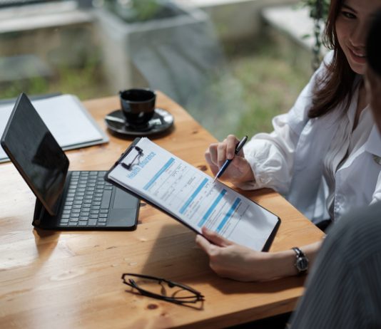 Digital Transformation in Insurance: Deploying Custom Software 60% Faster Female health insurance broker presenting his insurance benefits to businessman fill out insurance policy. Digital Transformation in Insurance