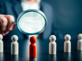 Magnifying success powerful red wooden businessman leading way. Identiying leader with potential concept