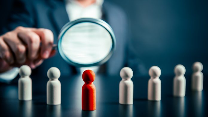 Magnifying success powerful red wooden businessman leading way. Identiying leader with potential concept