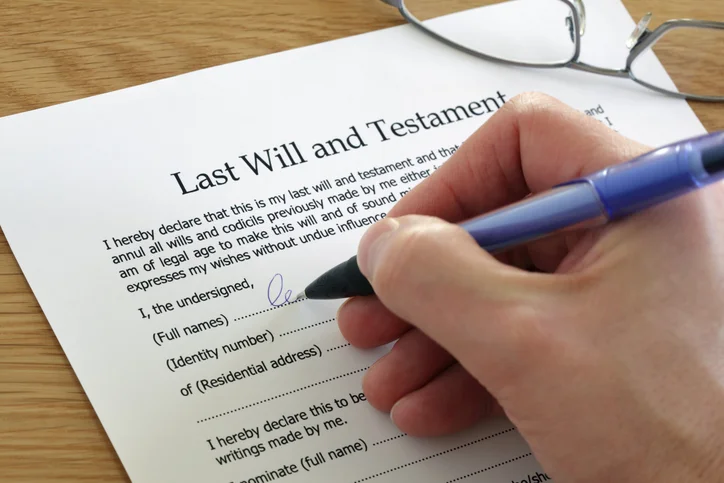 A hand signs a last will and testament, the first step in making it legally binding.