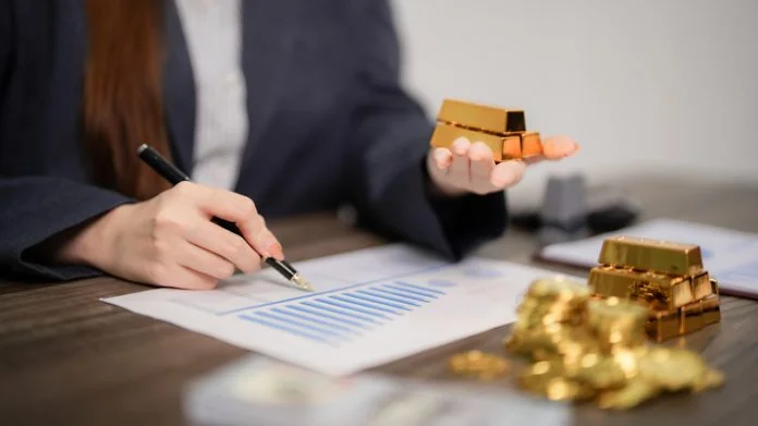 Businesswoman hands analyzing gold investment financial charts and market data on desk for strategic wealth management and precious metals trading Business Leaders Are Rethinking Precious Metals