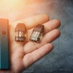 Vape pod system or pod mod with changeable cartridges close up in male hand.