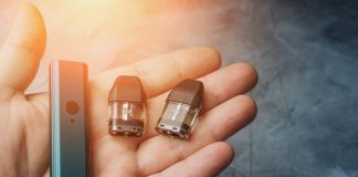 Vape pod system or pod mod with changeable cartridges close up in male hand.