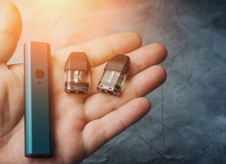 Vape pod system or pod mod with changeable cartridges close up in male hand.