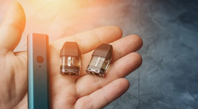 Vape pod system or pod mod with changeable cartridges close up in male hand.
