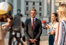 When Campaigns Hijack the Newsroom Horizontal shot of politician giving interview during campaign to journalists. People making interview using digital camera and equipment set at outdoor location.