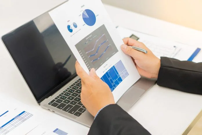 Businesswoman holding documents with financial statistics, stock photos, discussion and data analysis, charts and graphs with laptop computer. financial concept FPGA acceleration trading