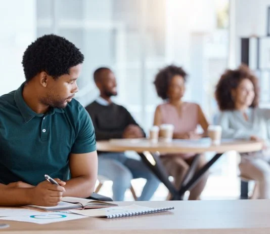 Reject, sad and antisocial professional employee sitting at his desk as outcast in the workplace. Workplace Microaggressions concept
