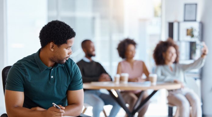 Reject, sad and antisocial professional employee sitting at his desk as outcast in the workplace. Workplace Microaggressions concept