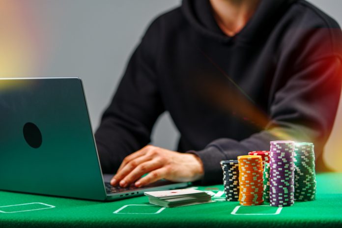 A player engages with online poker on a laptop, surrounded by colorful chips and playing cards on a green table Wins Online Turns Gameplay Into a Social Identity Signal