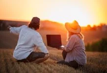 Backing Europe’s Farmers is Key to Scaling Climate-Smart Agriculture Farmers using laptop for smart farming analysis while observing rural field during sunset. Concept of modern agriculture and farm innovation