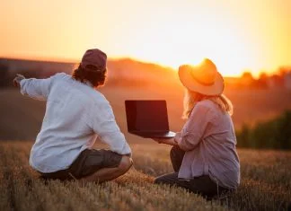Backing Europe’s Farmers is Key to Scaling Climate-Smart Agriculture Farmers using laptop for smart farming analysis while observing rural field during sunset. Concept of modern agriculture and farm innovation