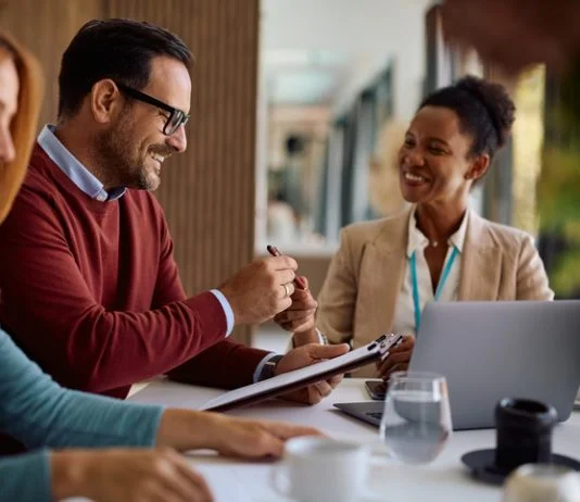 Happy couple coming to and agreement with their financial advisor. Focus is on man signing a contract following the Fiduciary Standard
