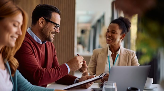 Happy couple coming to and agreement with their financial advisor. Focus is on man signing a contract following the Fiduciary Standard
