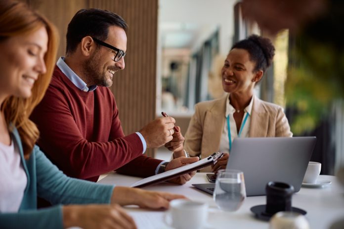 Happy couple coming to and agreement with their financial advisor. Focus is on man signing a contract following the Fiduciary Standard