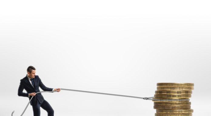 Businessman pulling stack of big golden coins with a rope isolated on white background. Making money. Profit and advantage. Earning a fortune.