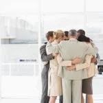 Business people hugging in a circle in the office. Compassion and accountability concept