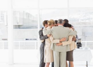 Mastering the Compassion-Accountability Paradox: A Practical Framework for Leaders Business people hugging in a circle in the office. Compassion and accountability concept