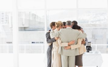 Business people hugging in a circle in the office. Compassion and accountability concept