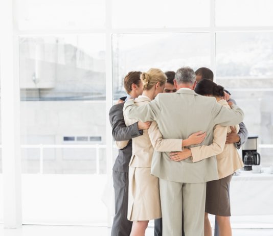 Business people hugging in a circle in the office. Compassion and accountability concept