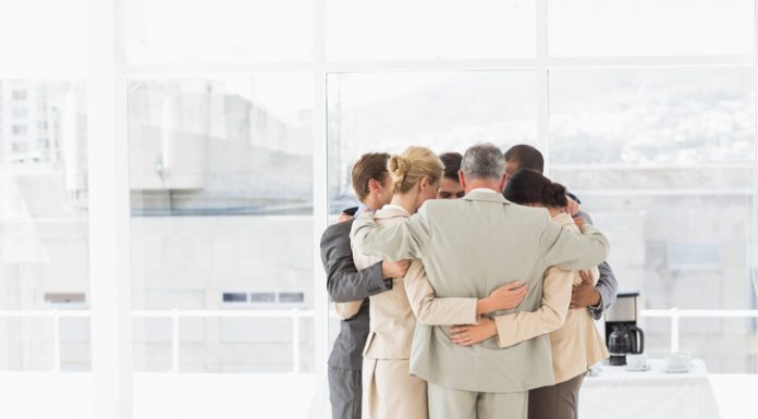 Business people hugging in a circle in the office. Compassion and accountability concept