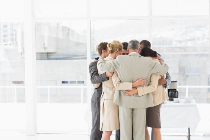 Business people hugging in a circle Business people hugging in a circle in the office. Compassion and accountability concept