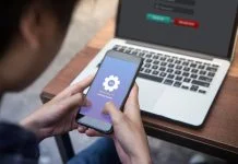 While working on laptop businessman installing OTA firmware update his smartphone at outdoor cafe