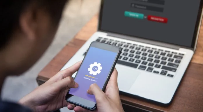 While working on laptop businessman installing OTA firmware update his smartphone at outdoor cafe