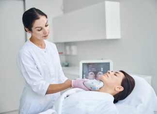 Experienced female dermatologist using a Ultherapy Prime beauty device for tightening the skin on her patient neck