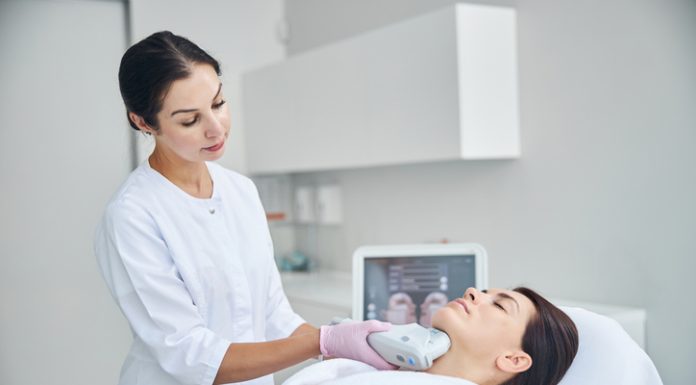 Experienced female dermatologist using a Ultherapy Prime beauty device for tightening the skin on her patient neck