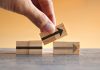 Small Changes that Improve Business Efficiency Hand holding wooden cubes with arrow icon. New strategy, changes, alternative path, and improvement. Small Changes for Big Business concept
