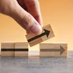Small Changes that Improve Business Efficiency Hand holding wooden cubes with arrow icon. New strategy, changes, alternative path, and improvement. Small Changes for Big Business concept