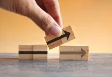 Hand holding wooden cubes with arrow icon. New strategy, changes, alternative path, and improvement. Small Changes for Big Business concept