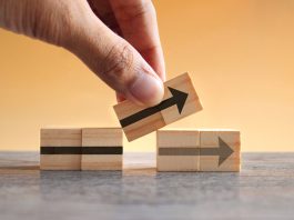 Hand holding wooden cubes with arrow icon. New strategy, changes, alternative path, and improvement. Small Changes for Big Business concept