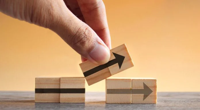 Hand holding wooden cubes with arrow icon. New strategy, changes, alternative path, and improvement. Small Changes for Big Business concept